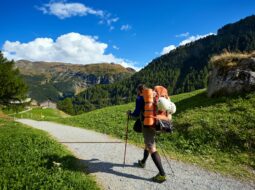 Solo traveler walking along a mountain trail, representing handling change, adaptability, and personal growth.